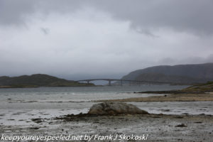 clouds over bridge and rocky beach 